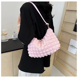 Detail view of pink bubble texture shoulder bag showing pleats and popcorn fabric on a model