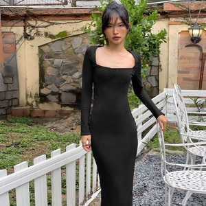 Détail d'une robe longue noire ajustée avec décolleté carré et petit nœud décoratif