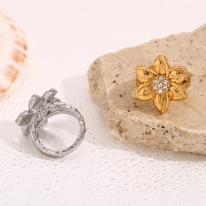 Detailed view of 18K gold and silver floral rings with cubic zirconia crystal centers