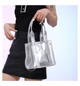 Detail der silbernen Metallic-Tasche mit Steppmuster und modischen Buchstabengurten