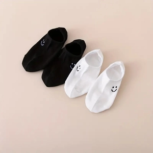 Close-up of low-cut cotton socks with minimalist embroidered smile faces in black and white