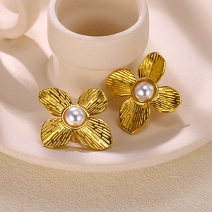 Macro view of gold flower earrings with silk texture petals and white pearl center