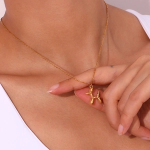 Detailed view of an 18K gold plated 3D balloon dog pendant necklace on a female model