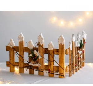 Detail of wooden Christmas fence with faux snow, pine needles, red berries and pinecones