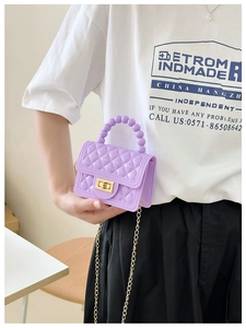 Purple quilted jelly bag detail with pearl handle and gold chain strap held by model