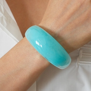 Detailed view of translucent turquoise resin wide bangle with polished smooth finish
