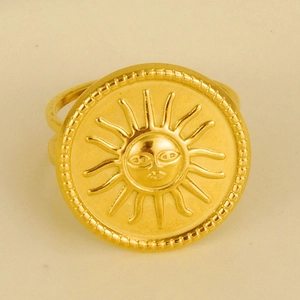 Macro detail of the embossed sun face totem on a golden 18k plated stainless steel ring