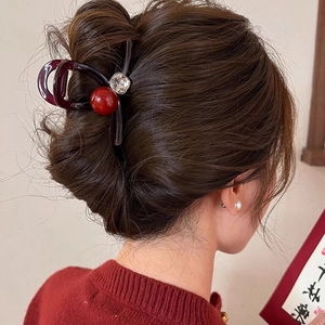 Grande pince à cheveux rouge en acrylique avec perle vue sur cheveux de femme