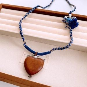 Close-up of heart-shaped wooden pendant with colorful braided rope and blue tassels