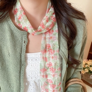 Detailed macro view of an elegant floral mesh skinny scarf paired with a green cardigan.