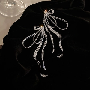 Détail de boucles d'oreilles nœud en argent avec longues franges sur fond en velours noir