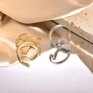 Detail of adjustable gold and silver hugging hands rings on a premium silk background