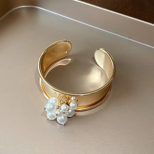Elegant gold cuff bracelet featuring clustered white pearls with an open adjustable design