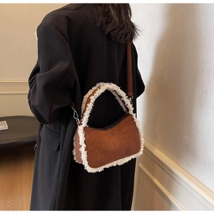 Detail of lamb wool trim on a brown suede shoulder bag with soft textured stitching