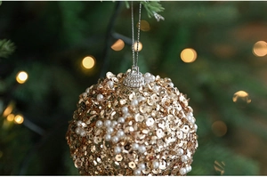 Detail view of 8cm gold sequin Christmas ball with pearls on a festive tree branch