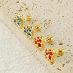 Orecchini a cuore dorati con strass rossi e blu su uno sfondo di pietra naturale