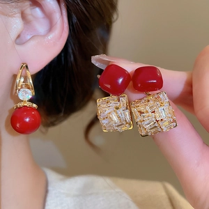 Détail de boucles d'oreilles vintage avec zircon rouge, finition dorée et résine carrée
