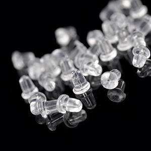 Macro detail of clear silicone earring back stoppers scattered on a black background
