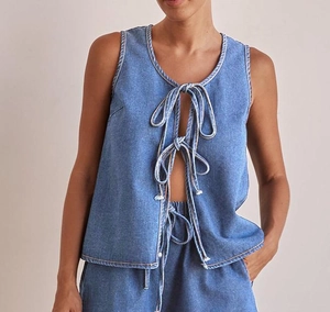 Detail of blue denim vest featuring three front ties and contrast stitching accents
