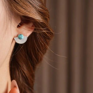 Close-up of vintage fan-shaped silver earring with turquoise stone on model