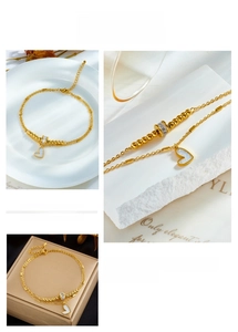 Detail of layered gold ankle bracelet with heart pendant and mother-of-pearl inlay