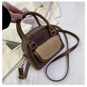 Detail view of brown faux suede handbag with beige plush trim and top handle strap