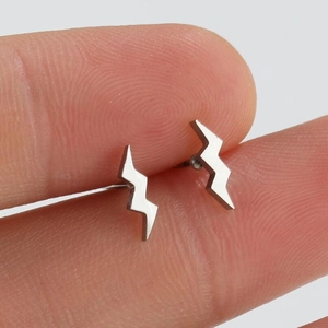 Minimalist silver lightning bolt stud earrings shown between fingers for size reference