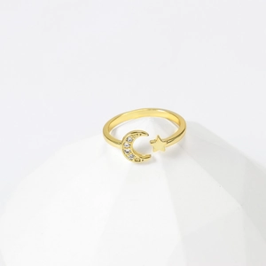 Minimalist gold moon and star open ring with sparkling cubic zirconia on a white stand