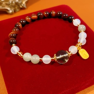 Macro detail of bead bracelet with tiger eye stones and a gold lucky charm tag