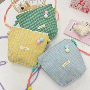 Three colorful woven crossbody phone bags with pom poms and rope straps detail