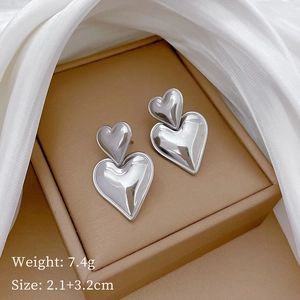 Detailed view of polished silver double heart earrings on elegant satin display