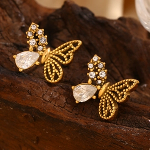 Macro shot of gold-plated butterfly earrings with half-winged cubic zirconia inlay detail