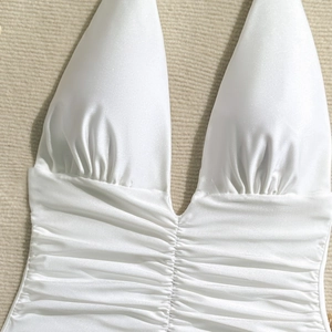 Close-up of white deep V-neck halter swimsuit with elegant ruching details