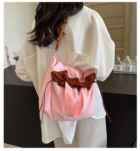 Dettaglio della borsa tote in nylon rosa e marrone con coulisse indossata da una modella