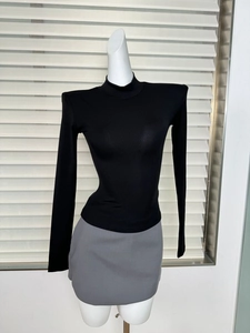 Detail von engem schwarzem Langarmshirt mit Schulterpolstern und Stehkragen am Mannequin