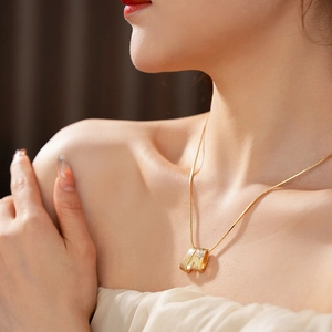 Close-up of gold necklace with irregular brushed pendant and zircon on female model
