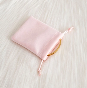 Detailed view of pink velvet drawstring jewelry pouch with gold bracelet on faux fur