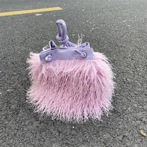Detail of light purple faux fur bucket bag with smooth PU leather drawstring on asphalt