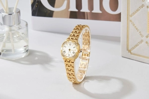 Detail of luxury gold quartz watch with diamond-encrusted bezel and blue gemstone crown