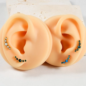 Detail view of gold-plated curved ear studs with five gradient opal stones on ear models