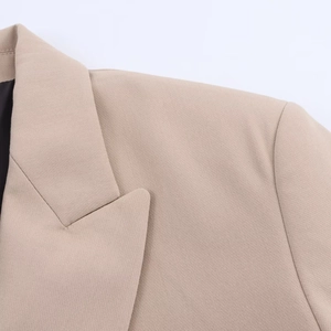 Detail of beige blazer collar and shoulder area showing fine woven fabric texture