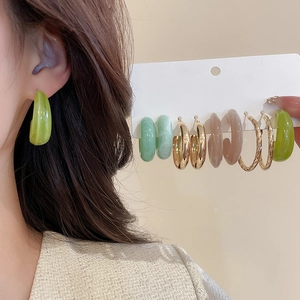 Gros plan d'un ensemble de boucles d'oreilles C en acrylique vert et doré