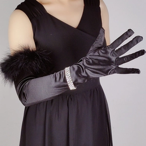 Detailed view of long black satin gloves with feather cuffs and sparkling rhinestone bracelet