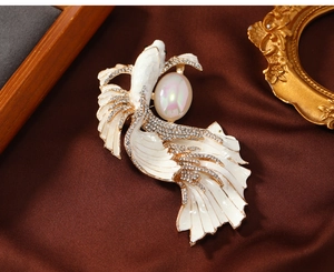 Detail of vintage koi fish brooch with white enamel scales and pearl eye on silk