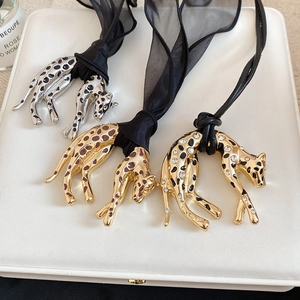 Detailed view of leopard pendants in gold and silver finish with enamel and rhinestones