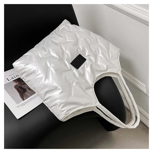 Detail of white quilted tote bag with Y-shaped geometric patterns and fashion label