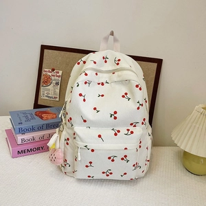 Close-up of corduroy backpack with cherry pattern on a desk with aesthetic props