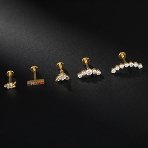Set de piercings cartilage F136 titane doré avec feuilles et zircons sur fond sombre