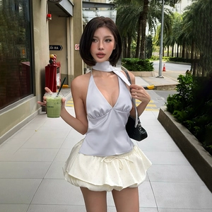 Top dos nu en satin gris argenté avec une mini-jupe blanche à volants étagés
