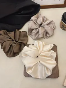 Detailed view of oversized satin scrunchies in coffee, champagne, and dusty rose tones